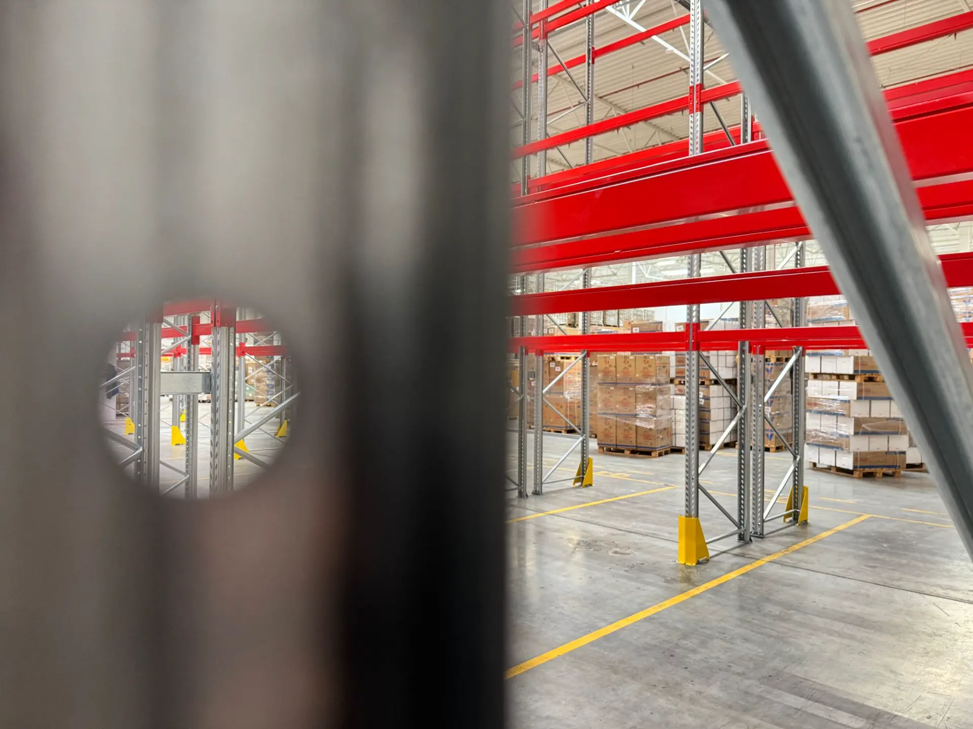 Langowski Logistics Łódź: Magazyn wysokiego składowania z czerwonymi regałami, pustymi paletami i żółtymi oznaczeniami.