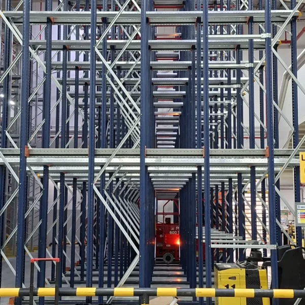 NESTLE - CEREAL PARTNERS POLAND TORUŃ-PACIFIC: Wnętrze magazynu wysokiego składowania z regałami, wózkiem widłowym i sprzętem.