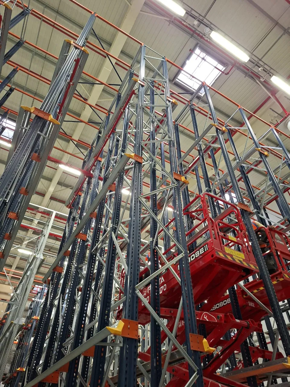 NESTLE - CEREAL PARTNERS POLAND TORUŃ-PACIFIC: Instalacja wysokiego regału magazynowego z dwoma czerwonymi podnośnikami nożycowymi.