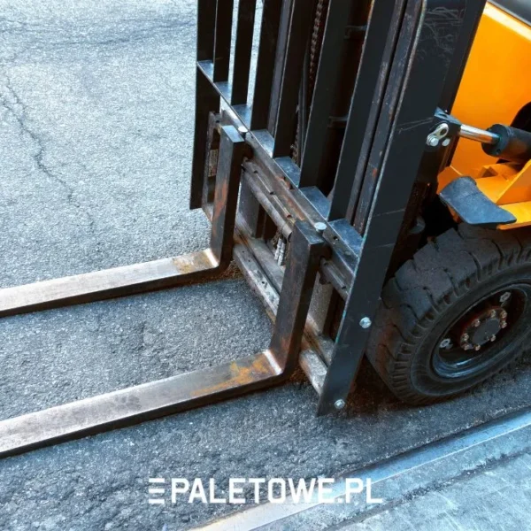 ile palet wejdzie na tira - Pomarańczowy wózek widłowy z czarnymi widłami i oponą na asfalcie. Napis: PALETOWE.PL.